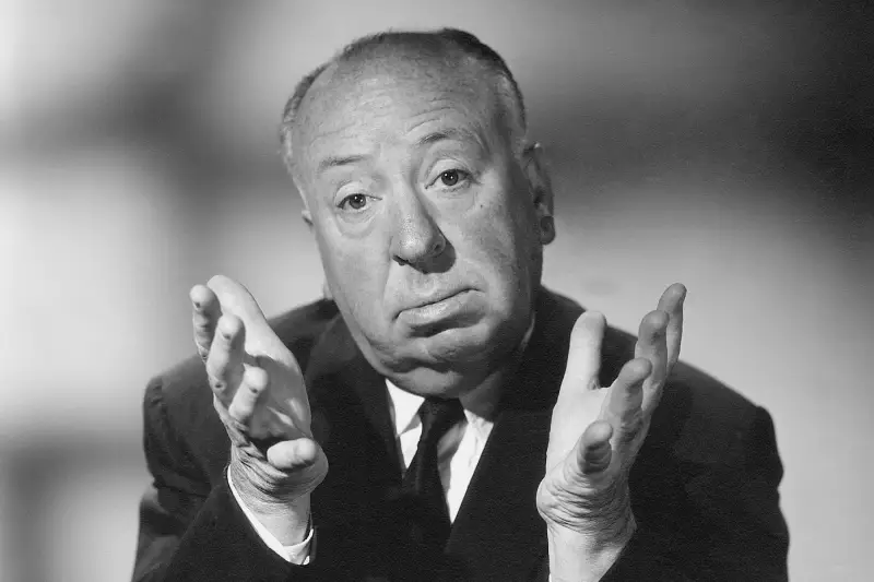 Portrait en noir et blanc d'Alfred Hitchcock, les mains levées devant lui